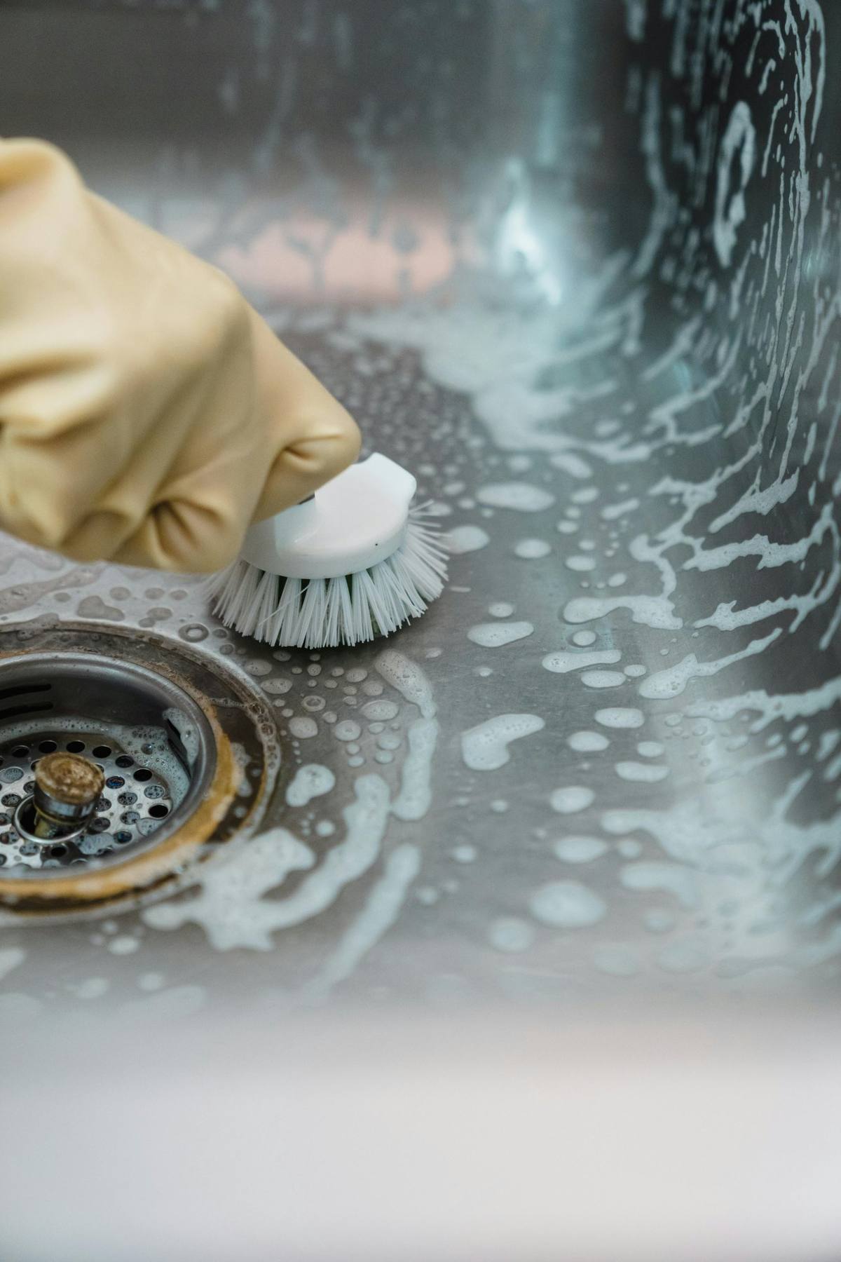 Scrubbing kitchen sink with brush and soap